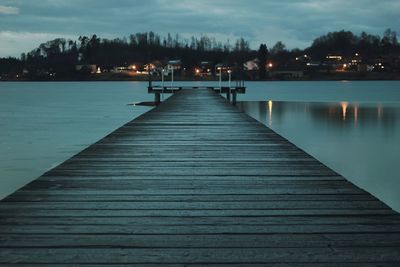 Pier over lake against sky at night