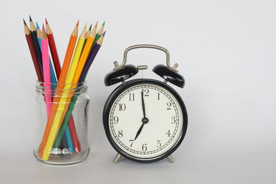 Close-up of clock on table against white background