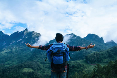 Rear view of man standing on mountain against sky