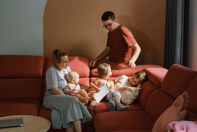 Big family on couch at home. parents with kids on sofa during sunny day spending free time. mother