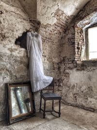 Old wedding dress hanging above chair and mirror