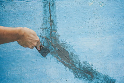 Close-up of hand holding blue wall