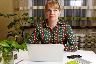 Mature woman working on computer at home. start or finish of a work day. young lady seating at the