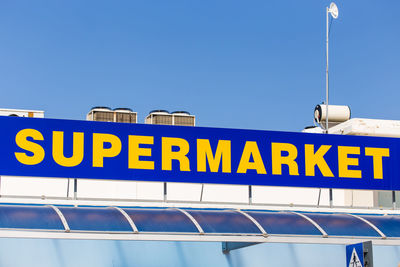 Low angle view of information sign against clear blue sky