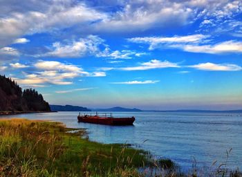 Boats in sea against cloudy sky