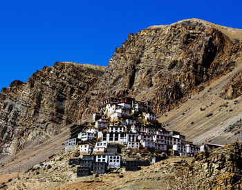 Low angle view of buildings on mountain against rock formations 