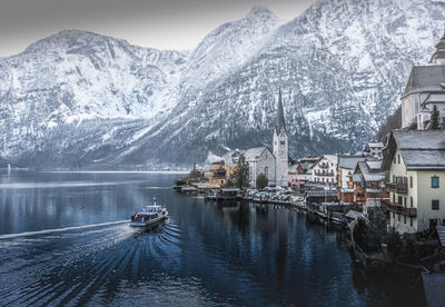 Scenic view of snowcapped mountains and building by lake