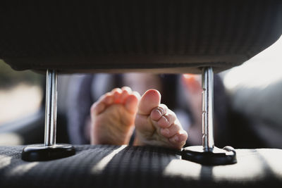 Close-up of girl's feet resting on vehicle seat in car