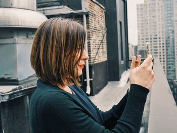 Woman taking photo with smart phone from rooftop balcony