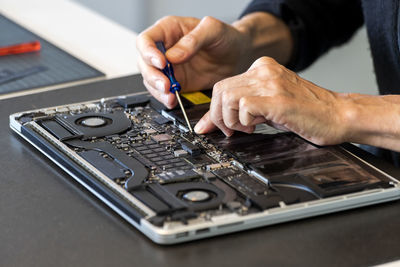 Man repairing laptop with screwdriver