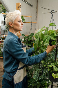 Side view of young woman holding potted plant