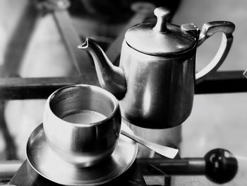 Close-up of tea cup with pot on table