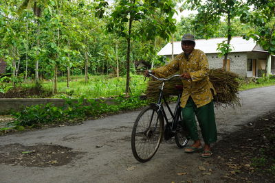 Man with bicycle standing by tree