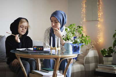 Mother wearing hijab helping son with add or adhd doing homework