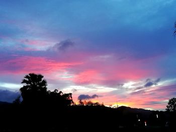 Silhouette trees against dramatic sky during sunset