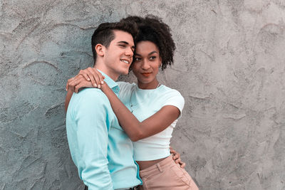 Portrait of a smiling young couple standing against wall