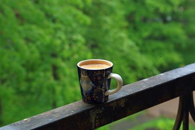 Close-up cup of coffee on railing against blurred background