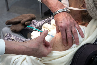 Doctor injecting covid-19 vaccine to senior women while sitting at vaccination center