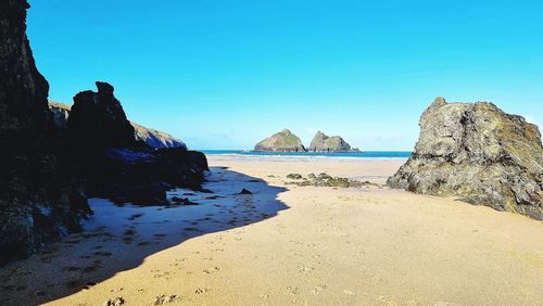 Rocks on beach against clear blue sky