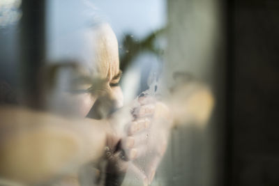 Close-up of pregnant woman with eyes closed in labor at home seen through window
