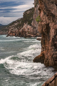 Rock formation by sea against sky