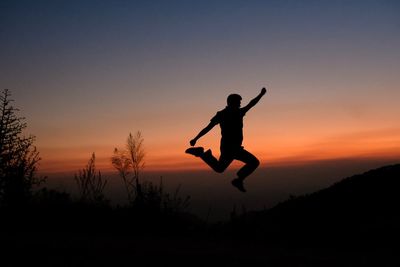 Silhouette man jumping against sky during sunset