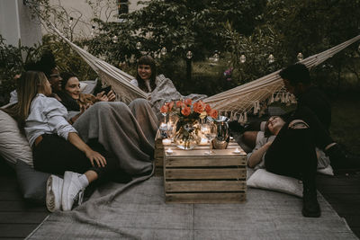 Smiling friends enjoying at social gathering in yard during sunset