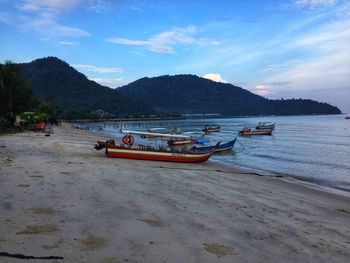 Boat moored on beach against sky