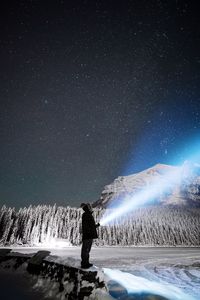 Man standing by frozen lake against star field at night