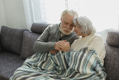 Senior couple cuddling on the couch under a blanket