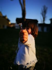 Girl holding flower against sky