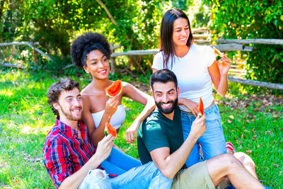 Male and female friends eating watermelon in backyard