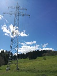 Low angle view of electricity pylon on field against sky