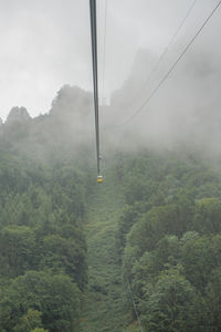 Overhead cable car over mountain against sky