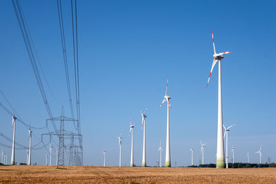 Windmills on field against clear sky