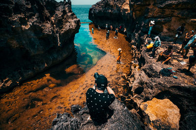 High angle view of woman sitting on rock at beach