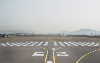 Road leading towards mountains against clear sky