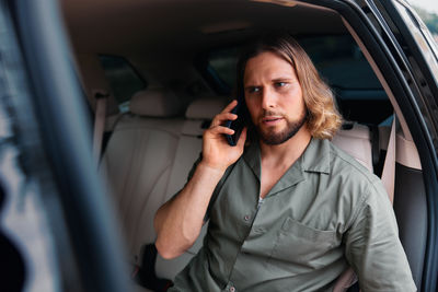 Portrait of young woman using mobile phone while sitting in car