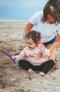 Smiling woman playing with daughter at beach