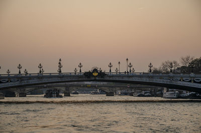 Bridge over river against clear sky during sunset