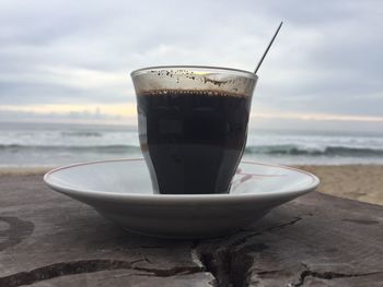 Close-up of coffee cup on beach