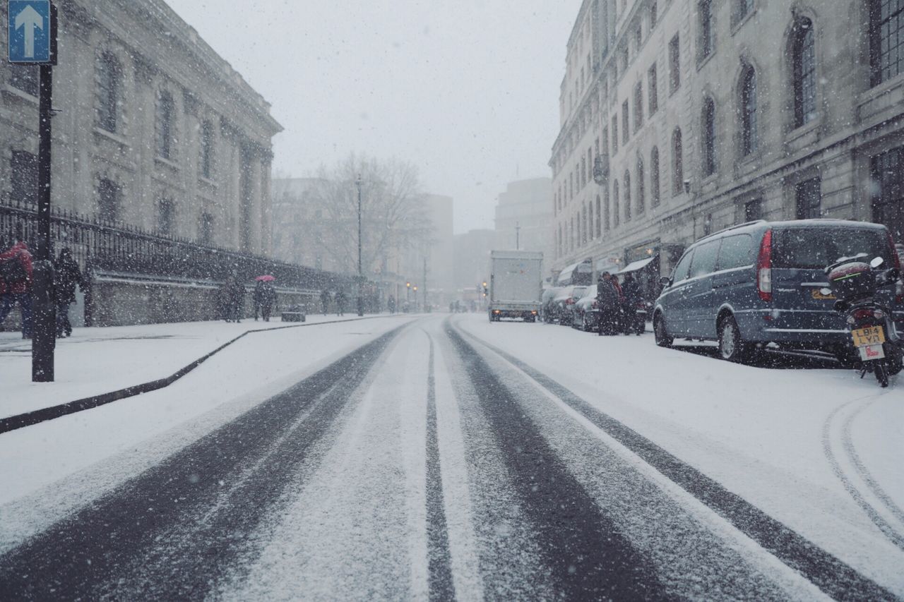 SNOW COVERED ROAD AMIDST BUILDINGS IN WINTER