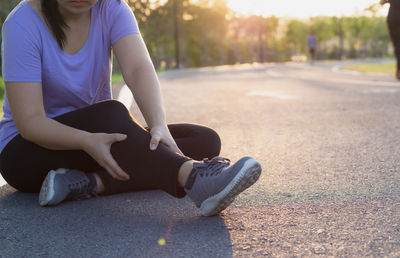 Low section of woman sitting on road