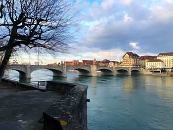 Bridge over river against sky in city at sunset