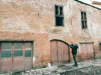 Rear view of man standing on brick wall