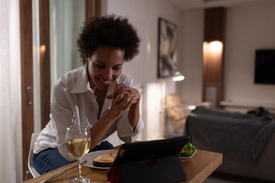 Happy ethnic woman having online date during dinner