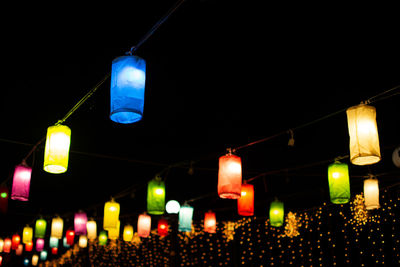 Low angle view of illuminated light bulbs hanging on street