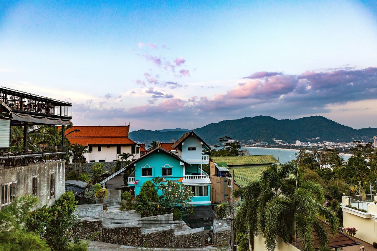 building exterior, architecture, built structure, house, sky, residential structure, mountain, blue, residential building, town, residential district, townscape, sea, tree, cloud - sky, roof, cloud, high angle view, water, nature