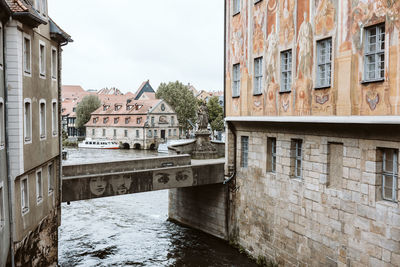 Arch bridge over river amidst buildings against sky