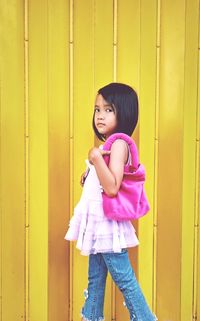 A little girl with pink handbag against the yellow background